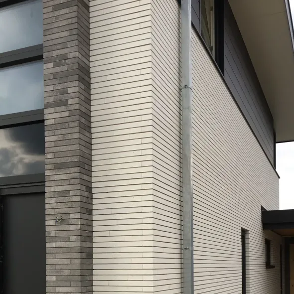 Išskirtinio ilgio apdailos klinkerinės plytelės derinyje su pilko atspalvio mūro detalėmis