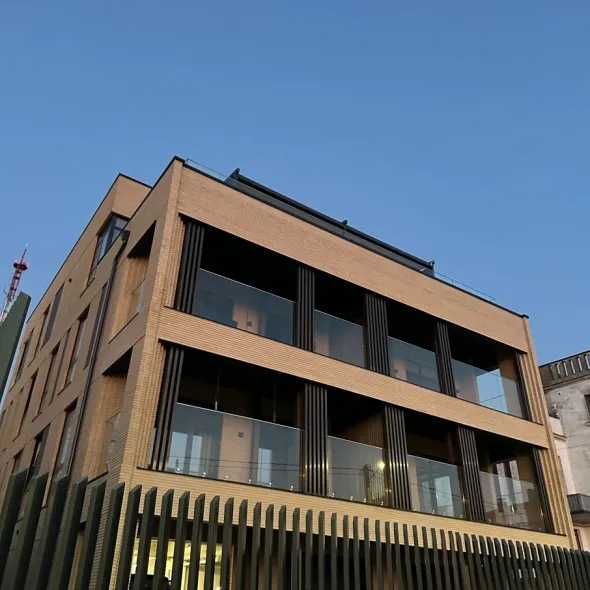 Itin ilgos tiesios ir siauros gelsvo smėlio spalvos plytos prabangiame fasade su stikliniais balkonais