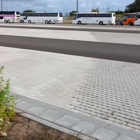 Linijinių ažūrinių eco betoninių trinkelių danga autobusų stovėjimo aikštelėje šalia asfalto