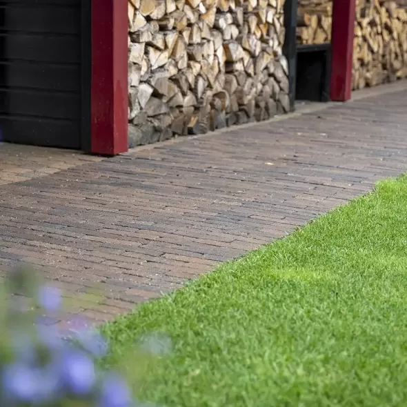 Jaukų ir solidų vaizdą sukuriantis kiemo takelio grindinys iš šiltai rudų klinkerio formato trinkelių