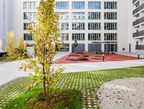 Organiškų vingiuotų formų ažūrinių eko betoninių trinkelių ornamentinis grindinys su žaliuojančia veja daugiabučių kieme