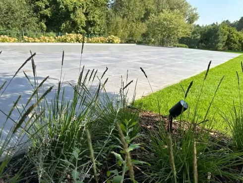 Tamsiai pilkos antracito spalvos Geokeramika Geoceramica lauko plytelės kieme šalia baseino smilgų bei šviestuvo