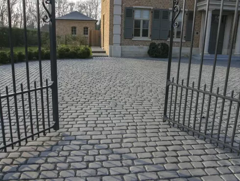 Gilaus tamsiai pilko atspalvio akmens imitacijos betoninių trinkelių kiemo grindinys už vartų